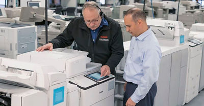 image of two men working on a Canon printer