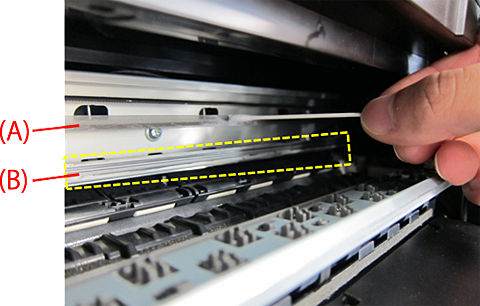 Encoder film (A) and rail (B) shown. Image shows person cleaning A with a cotton swab, without touching the inner parts with is hand.