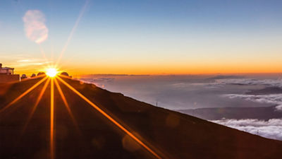 A view of the Earth from space with the sun just rising over the edge with a bright flare.