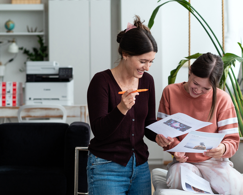 Two girls smiling and looking at paper