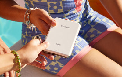 Two people hold a Canon IVY Mini printer in their hands
