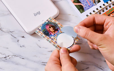 A person peels a circular sticker off its sticky back