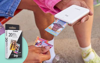 A person holds the Canon IVY mini printer while it prints photos