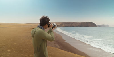 Man taking on beach taking horizon photo