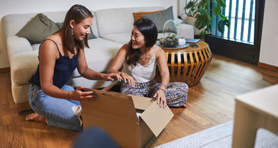 Two women opening a package in a living room