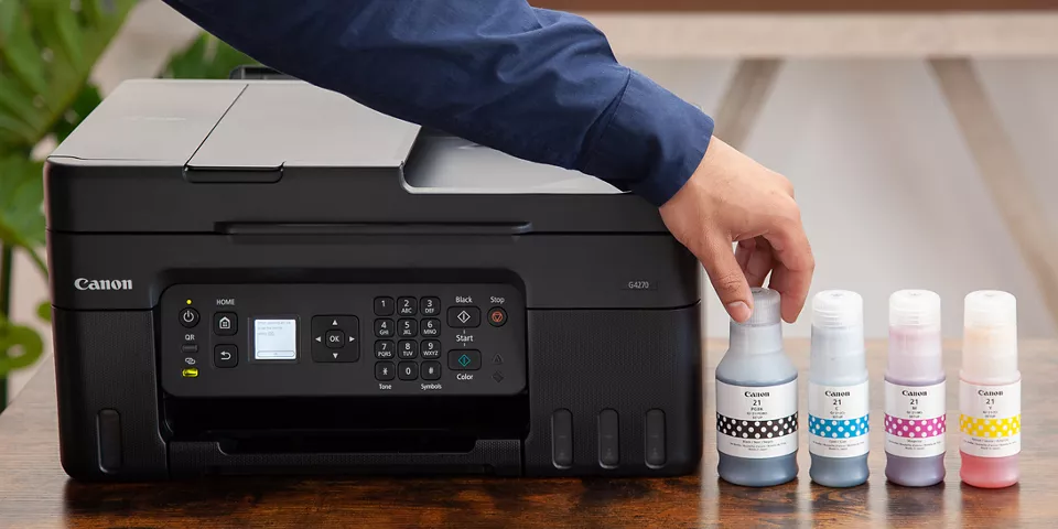 Person putting down the GI-21 Ink Bottles next to the PIXMA G4270 Printer