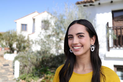 Person Smiling in Front of White Stone Apartment