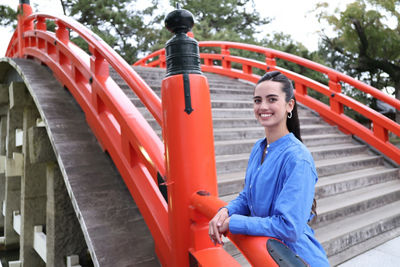 Person in a Blue Shirt Posing in Front of a Bridge