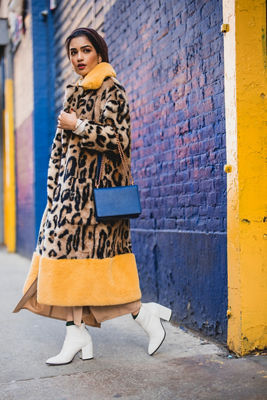 Dark haired model posing in a long jaguar print coat