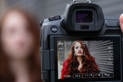 Red-haired model seen through viewfinder on camera