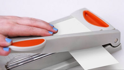 Hand using a paper trimmer to cut a small 2 x 3 inch piece of white cardstock.