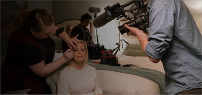 cameraman filming a makeup artist helping a client get ready