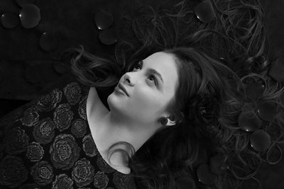 Black and white low key image of a model lying on her back with her hair fanned out around her wearing a floral top