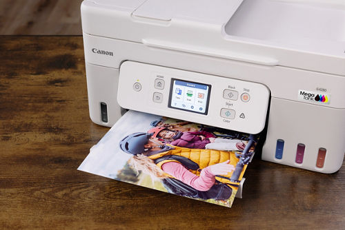 Canon printer printing a photo of people in helmets; MegaTank ink system visible.