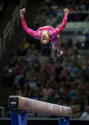 A gymnast doing a flip during her balance beam performance