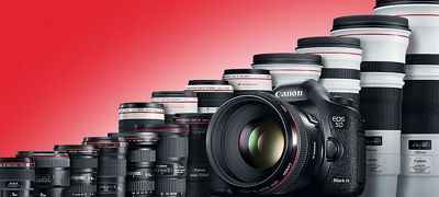 Canon camera in front of stacked camera lenses