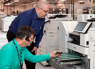 Two men working on a Canon printer