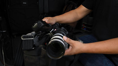 hands of man holding a camera by the lens