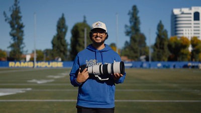Person Holding Canon Camera and Lens in a Football Field