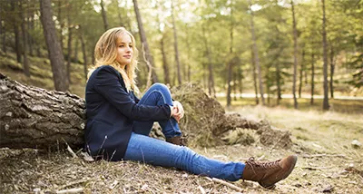 Woman sitting on ground against a log