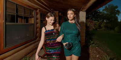 two girls in party dresses, with one holding a Canon camera