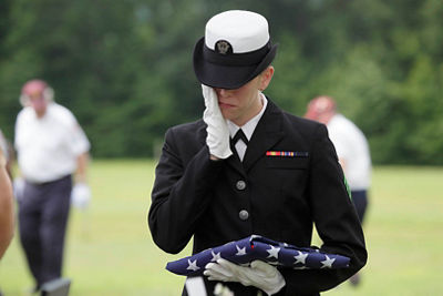 A soldier holding a folded flag