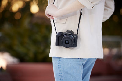 EOS R100 with RF-S18-45mm F4.5-6.3 IS STM Being Carried by a Strap