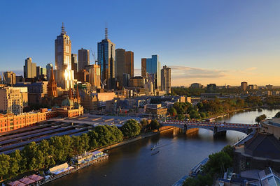 Aerial shot of a city with the sun shining off the glass buildings and a  blue sky beyond