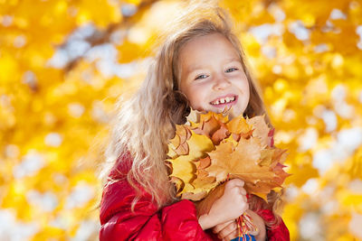 little girl holding a bundle of orange, yellow and red leaves