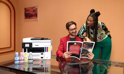 Person Holding a Magazine Next to PIXMA Printer