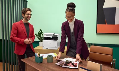 Person Holding Papers Next to PIXMA Printer