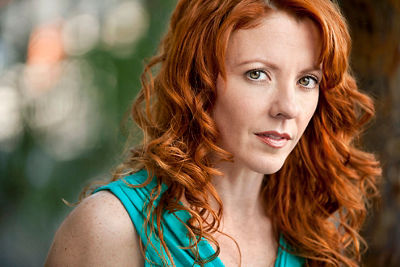A young woman, with red hair and a light blue top