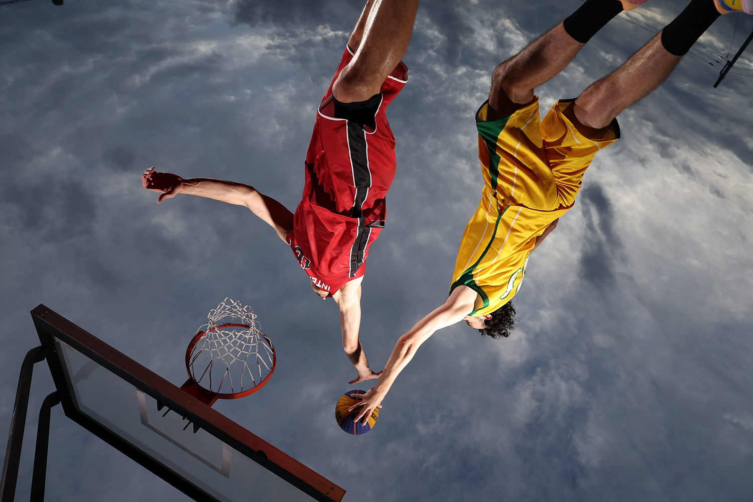Basketball Players Jumping Towards a Basketball Hoop