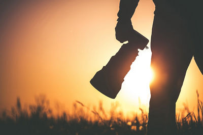 Close-up of a person walking through a field holding a camera with a red overlay on the image