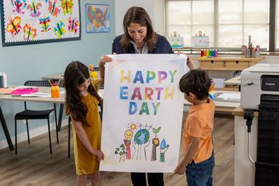 Profesora mostrando a los niños un cartel impreso