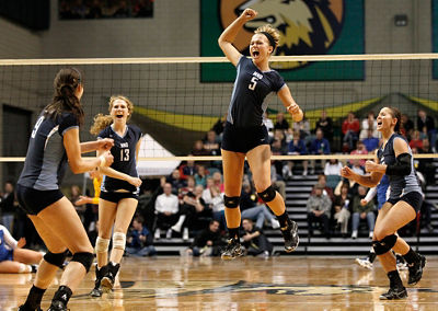 Volleball action shot - one woman celebrating by jumping into the center of her teammates on the court