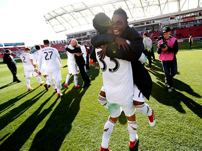 Soccer action shot - team walking across the field after a match - camera focused on two friends embracing