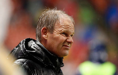 Soccer coach looking out anxiously at the game in a wet raincoat