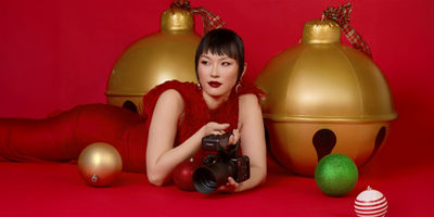 lady in red dress lying on the floor next to ornaments holding a canon camera