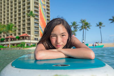 Laura's daughter lying on her wakeboard with the resort in the background