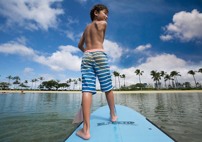 Laura's son standing on a wakeboard in the water