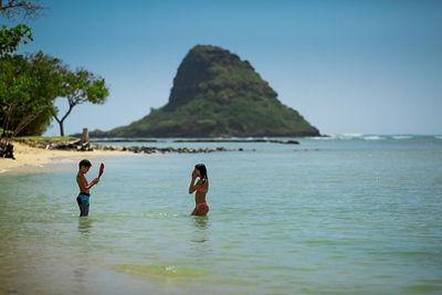 Laura's kids in the water with Chinaman's Hat enlarged in the background
