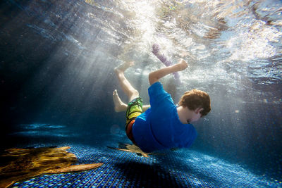 Boy falling through water in a pool