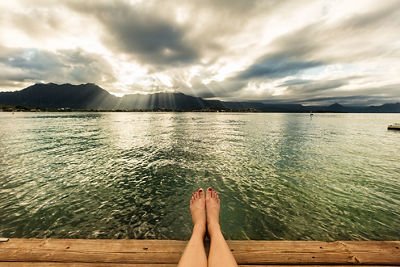 Sun rays on a mountain with feet dangling out over the water