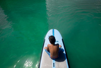 Overhead shot of Laura's son sitting on a wakeboard in the water