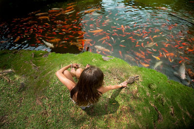 Overhead shot of Laura's daughter sitting next to a coy pond