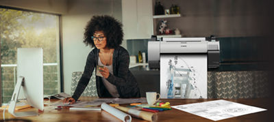 Woman working on computer at counter. Large format printer behind her