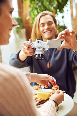 A person using a Canon EOS M50 to take pictures of someone plating gourmet food.