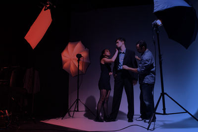 Professionals preparing man for photoshoot against a white backdrop