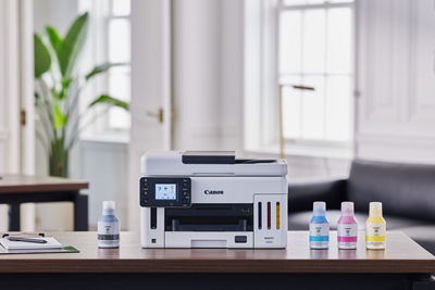 MAXIFY GX6110 - Front View on a Desk with Ink Bottles Next to it